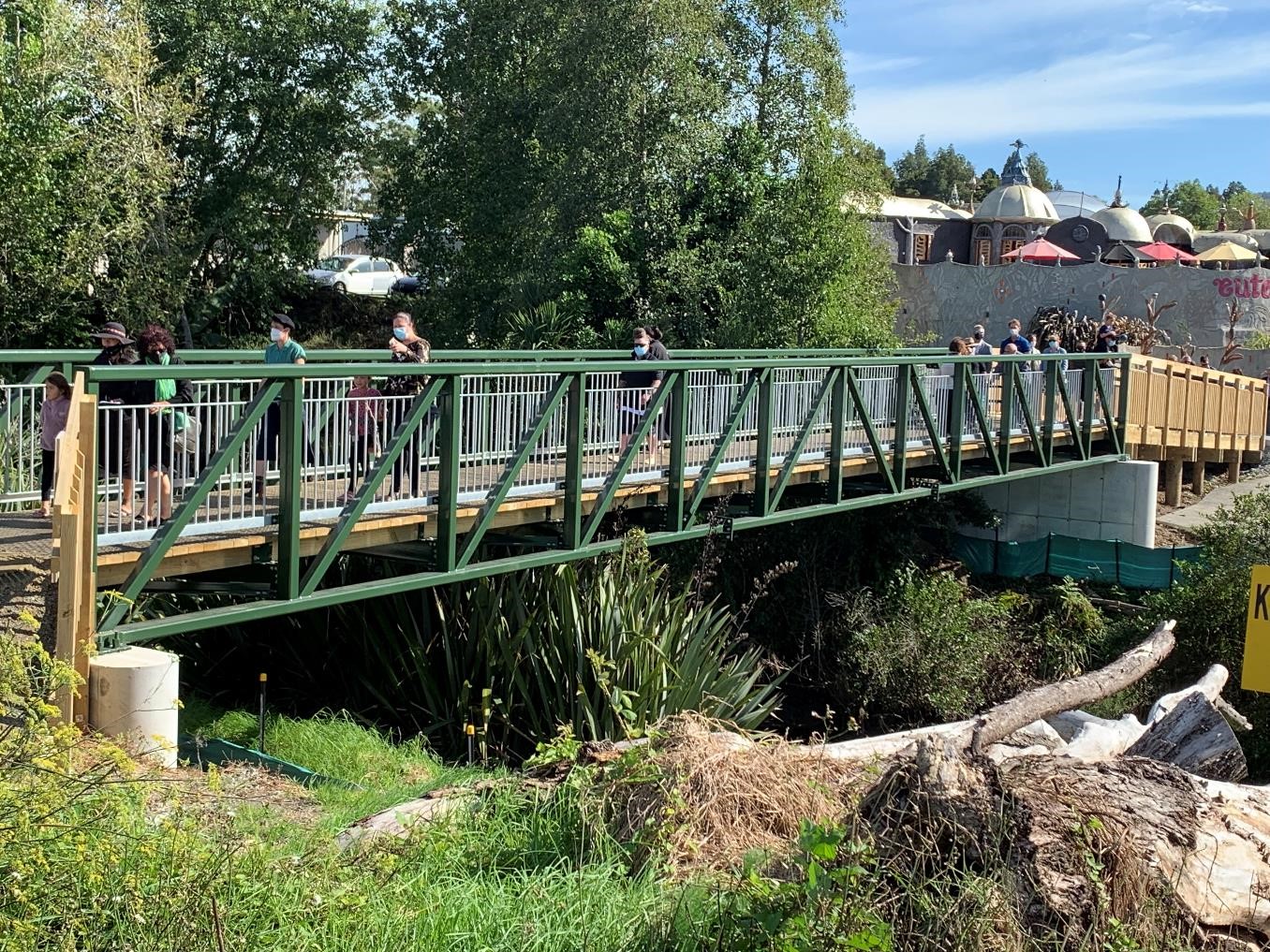 People are crossing the southern footbridge with Eutopia cafe in the background